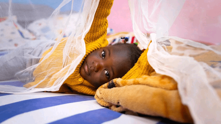 child-lying-on-bed-with-mosquito-net-in-cameroon-1536x864